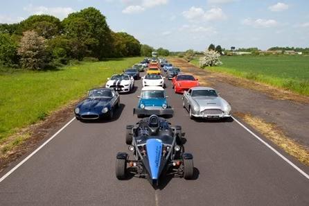 A convoy of supercars and classics on a quiet country road